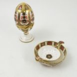 A Royal Crown Derby tea strainer and stand, together with an ornamental egg and cup,