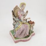 A Continental porcelain figure, of a woman seated in an open arm chair, next to a table,