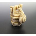 A Japanese Ivory Netsuke carved in the form of a snail climbing a bucket, signed to the base, c.