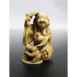 A Japanese Meji Period Carved Ivory Netsuke in the form of laughing Buddha with children at feet