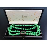 A Fine Jadeite Twin Strand Jade Necklace with seventy eight beads of uniform size and carved jade