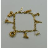 A 9 carat gold charm bracelet with nine charms including a stirrup, ice skate, the Eiffel Tower,