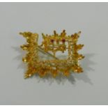 A Saudi Arabian yellow metal brooch of rectangular form, set with two small rubies (one lacking),