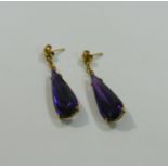 A pair of pear-shaped amethyst drop earrings, claw set in yellow metal mounts with stick backs,