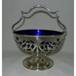 A George V silver basket with formal pierced decoration and blue glass liner,