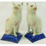 A pair of Stafforshire pottery cats, with printed floral decoration and seated on square bases,