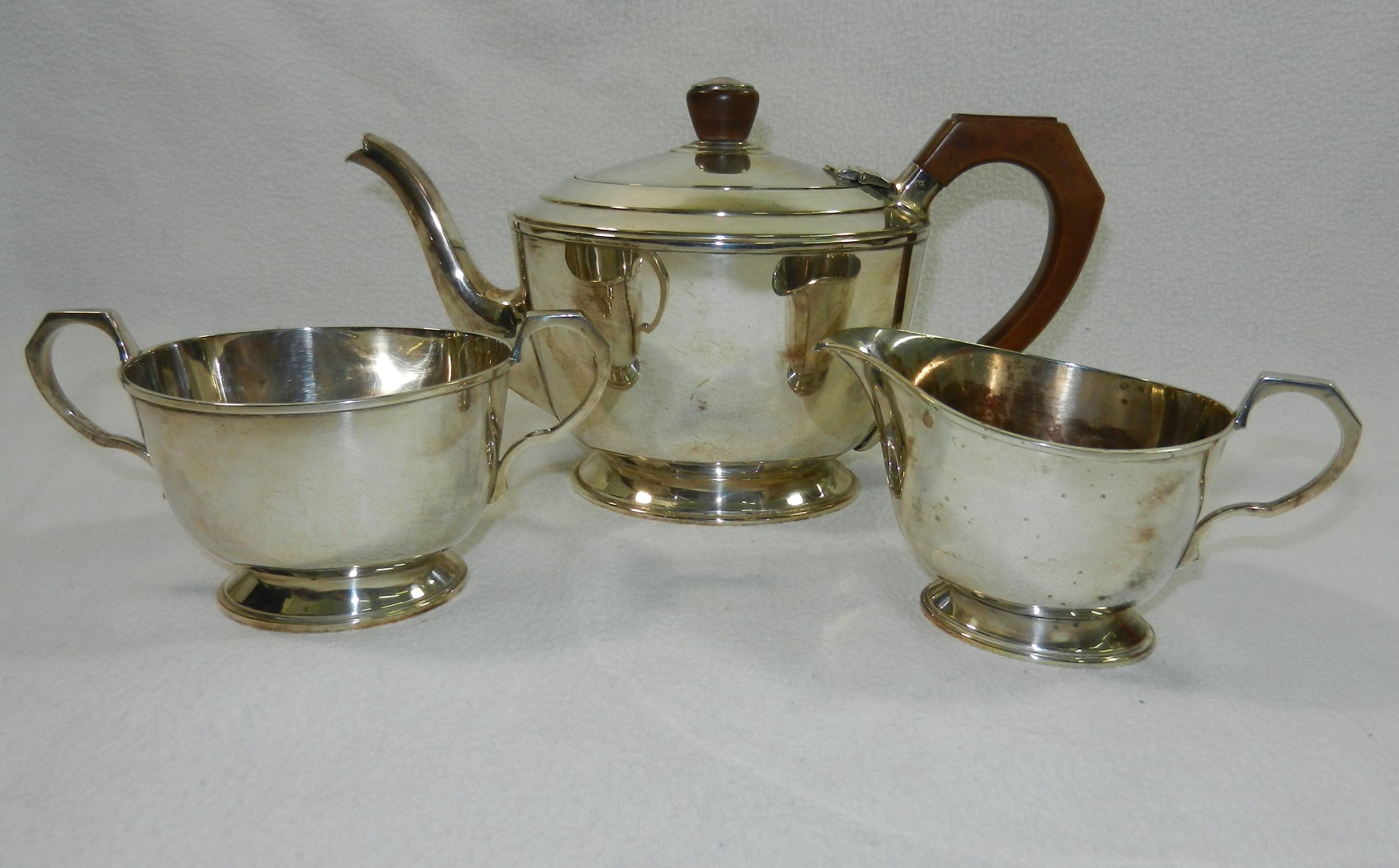 A silver three piece teaset comprised of a teapot with bakelite handle and knop,