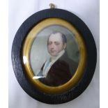 A 19th century oval portrait miniature of a gentleman, wearing a black coat,