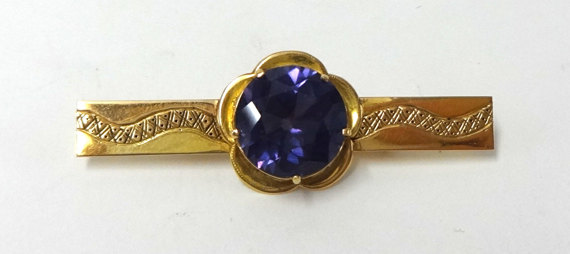 A yellow metal bar brooch set with a large amethyst stone, unmarked.