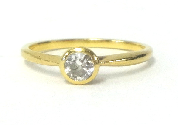 A diamond solitaire ring set in a yellow metal shank, size M.