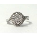 An 18ct white gold and diamond cluster ring, claw set with seven brilliant cut stones, diamond set