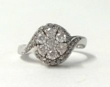 An 18ct white gold and diamond cluster ring, claw set with seven brilliant cut stones, diamond set