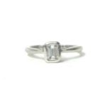 A platinum and diamond single stone ring, collet set with an emerald cut stone weighing 0.40cts,