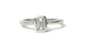 A platinum and diamond single stone ring, collet set with an emerald cut stone weighing 0.40cts,