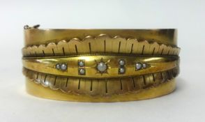 A yellow metal bangle, indistinctly hallmarked.