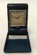 A small Swiss keyless travel clock, circa 1930/40 in folding leathered case.