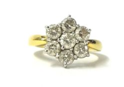 An 18ct gold and diamond cluster ring, claw set with seven brilliant cut stones, the shank stamped