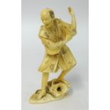 A carved ivory figure of a man with net (damaged), red seal mark to base height 12cm