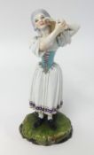 A 19th Century German porcelain figure of a women holding a vanity with blue cartwheel mark possibly