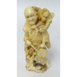 A carved ivory figure of a man with an instrument and a monkey upon his shoulder, height 9cm