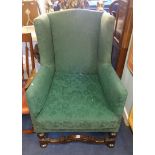 An antique wing backed upholstered arm chair.