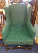 An antique wing backed upholstered arm chair.