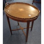 A mahogany oval side table with scalloped edging.