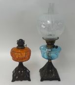 Two traditional oil lamps with coloured glass reservoirs.