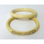 A carved ivory bangle, 10.50cm diameter and another (2)