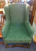 An antique wing backed upholstered arm chair.