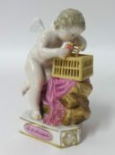 A porcelain figure, a winged cherub putting a bird into a cage on a plinth with a French