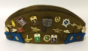 An old Army cap with various badges including Russian