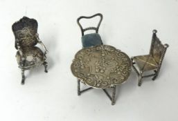 A miniature dolls house embossed silver table, 930 mark, and three chairs, approx 68.80g.