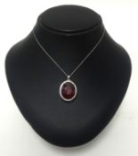 A 14K white gold and diamond pendant on an 18 inch 14K white gold chain set with an oval cut ruby