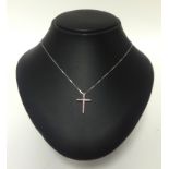 A white gold set diamond and pink sapphire set cross and fine chain.