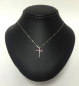 A white gold set diamond and pink sapphire set cross and fine chain.