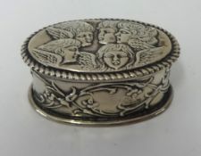 A silver oval snuff box embossed with winged cherubs' heads.