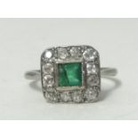 A platinum, emerald and diamond set square ring, size N.large chip to stone