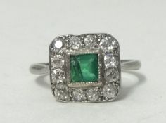 A platinum, emerald and diamond set square ring, size N.large chip to stone