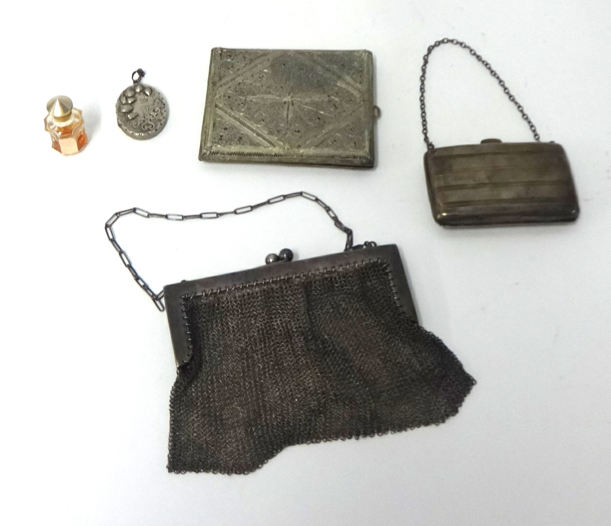 A small silver bag, an evening 'chain mail' bag, locket and miniature scent bottle.