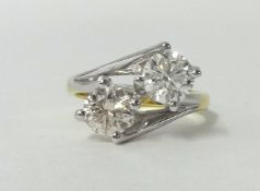 An 18ct yellow and white gold set two stone diamond crossover style ring, high 4 claw set, two round