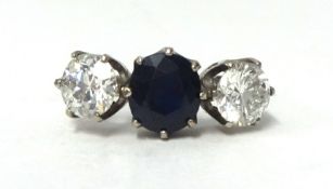 A fine antique three stone ring, set with a central sapphire and two round cut diamonds, each approx
