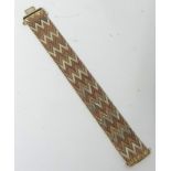 A 9K bracelet, yellow, white and rose gold in a chevron design, approx 66.10g, 19cm x 2cm.