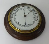 A circular aneroid barometer in wood frame.