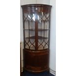 An early 19th century mahogany bow fronted corner display cabinet.
