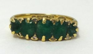 An 18ct antique five stone emerald set hoop ring, finger size N 1/2, 4.1gms.