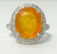 A white gold and diamond ring set with an oval cut orange sapphire, approx 7.50 carat, diamonds