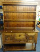 A 'stressed' oak dresser, in two parts with upper open shelves, the base fitted with drawers and