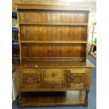 A 'stressed' oak dresser, in two parts with upper open shelves, the base fitted with drawers and