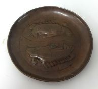 A Newlyn copper circular dish embossed with two fish.